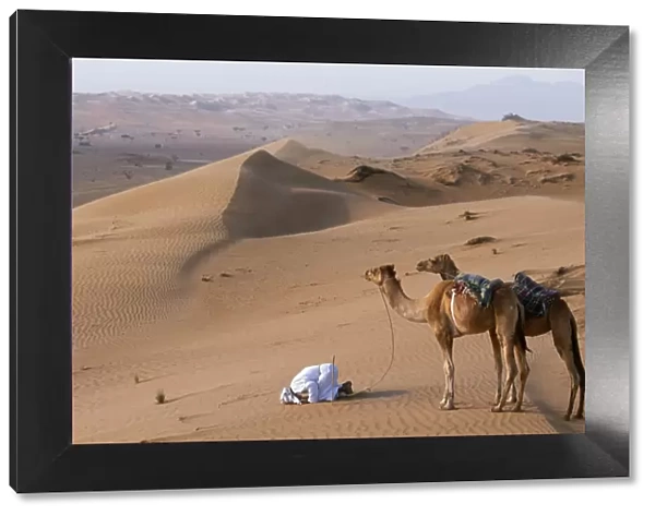 A Bedu kneels to pray in the desert