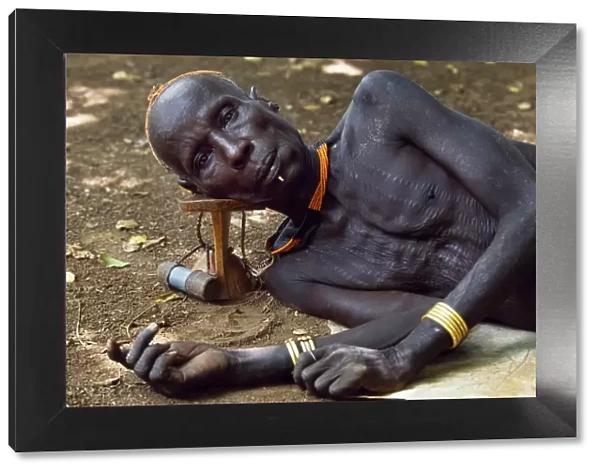 An elder of the Karo tribe rests with his head on his