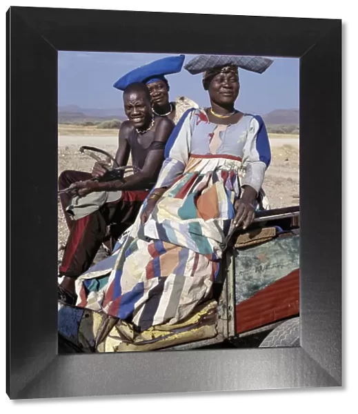 An Herero man and two women ride home in a donkey cart