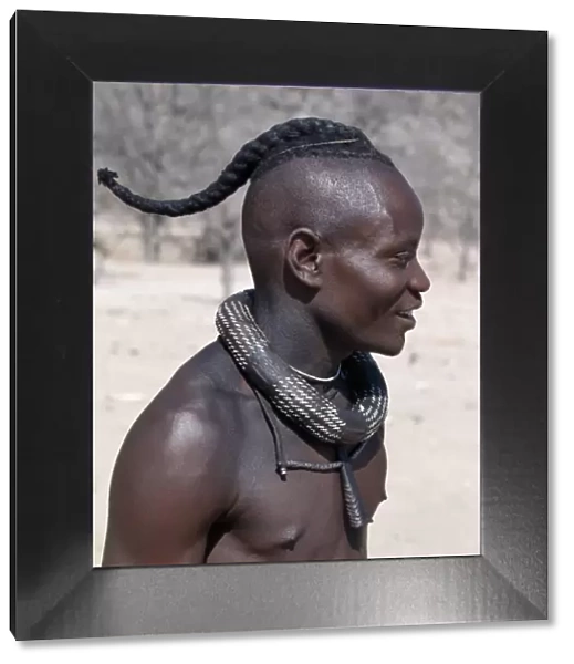 A Himba youth has his hair styled in a long plait, known as ondatu