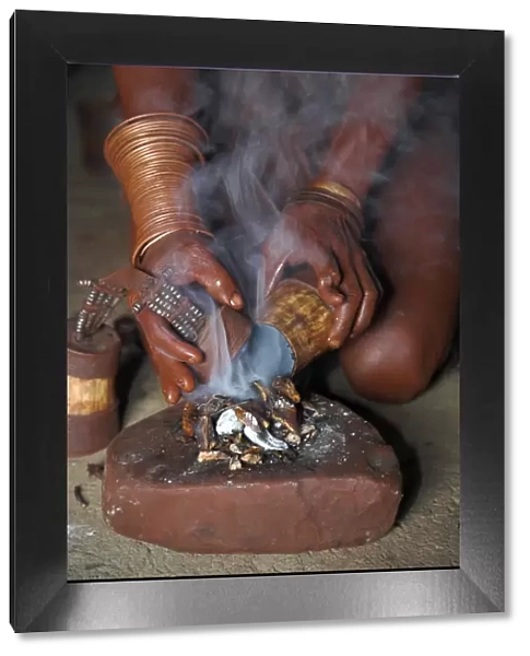A Himba woman lights a small fire made of woodshavings