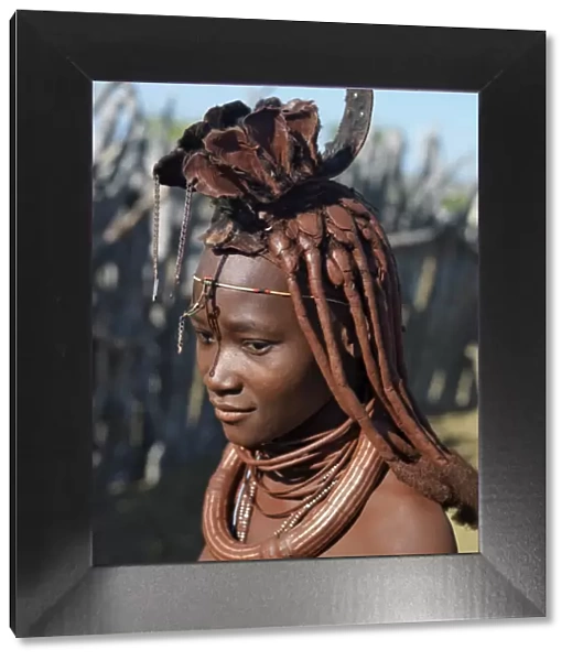 A Himba woman in traditional attire. Her body gleams from a mixture of red ochre