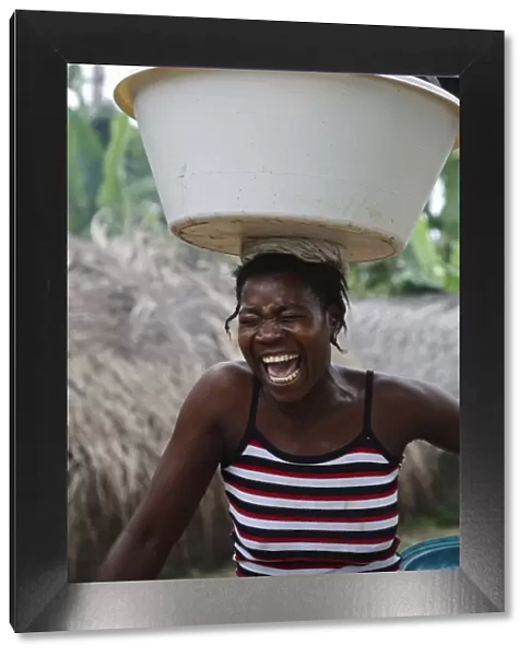 A Sao Tomense woman laughs while carrying her washing up on her head