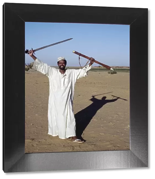 A Nubian man displays his sword at an oasis in the