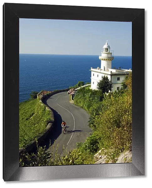 San Sebastian Bay Clifftop Lighthouse with Cyclist Riding uphill