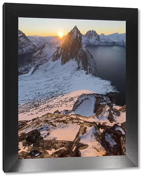 First lights of sunrise on Mount Segla and Mefjorden framed by the frozen sea seen