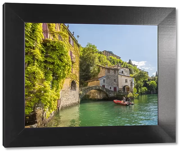 Nesso, lake Como, Como province, Italy. A small boat approaching the roman stone bridge
