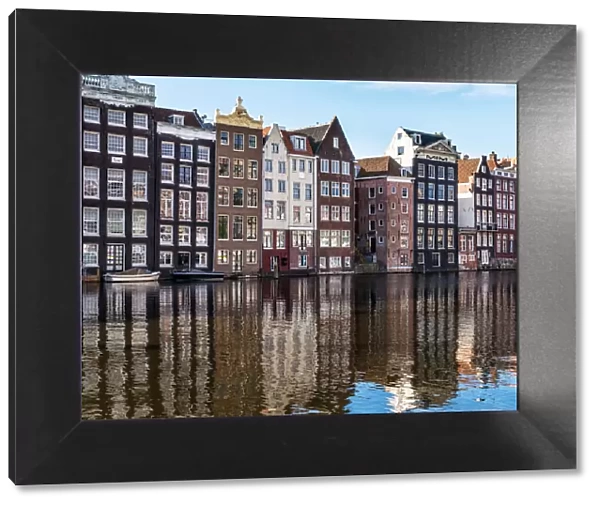 Traditional buildings along the Damrak reflected in the canal, Amsterdam, the Netherlands