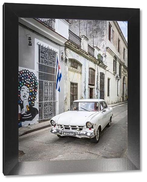 Classic car driving in a narrow street in La Habana Vieja (Old Town), Havana, Cuba