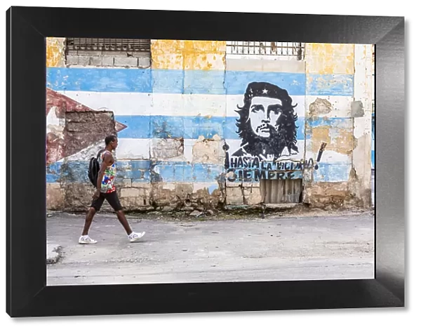 A man walking in a front of Che Guevara street art in La Habana Vieja (Old Town), Havana