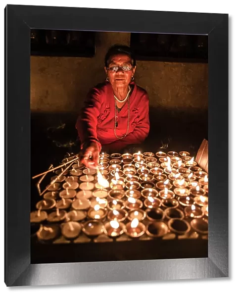 Woman lighting devotional candles in temple at Swayambhunath Stupa, Kathmandu, Nepal