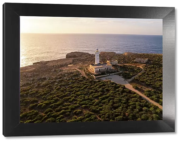 Drone view of the lighthouse Capo Murro di Porco standing on top of a cliff surrounded by Ionian sea at sunrise, Plemmirio marine park, Syracuse, Sicily, Italy