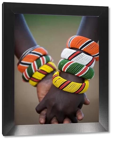 Kenya, Laikipia, Ol Malo. A Samburu boy and girl hold hands at a dance in their local manyatta