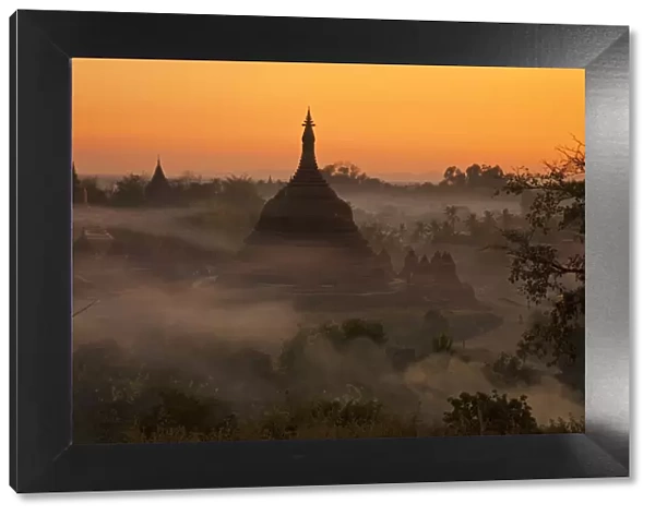 Myanmar, Burma, Mrauk U. Evening mist and smoke from village cooking fires swirl around Ratanabon Paya, Mrauk U