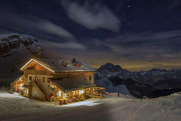 The Averau refuge in a wintertime night, surrounded by snow-covered peaks. Dolomites