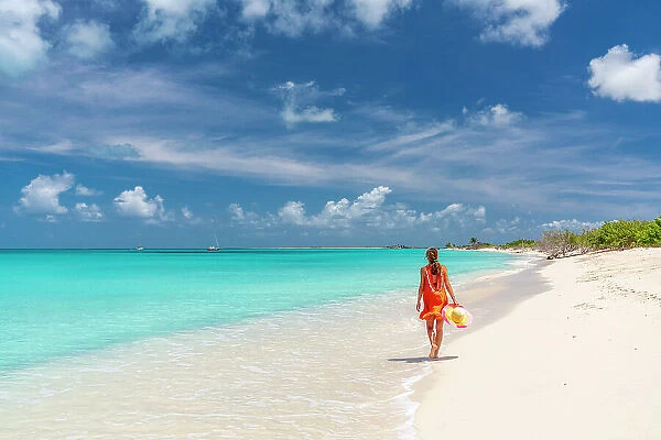 Beautiful woman in orange dress walking on a idyllic beach, Barbuda, Antigua & Barbuda, Caribbean, West Indies (MR)