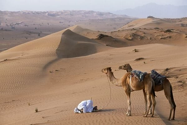 A Bedu kneels to pray in the desert