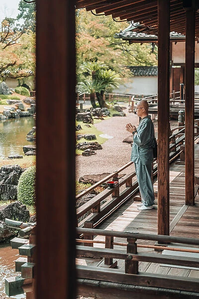Buddhist monk prays in front of the Japanese zen garden of Daigo-ji Temple, Kyoto, Japan