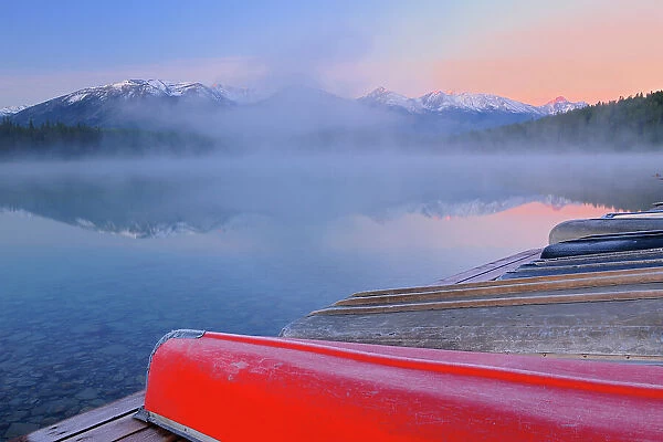 Canoes and Pyramid Lake in fog at dawn, Jasper National Park, Alberta, Canada