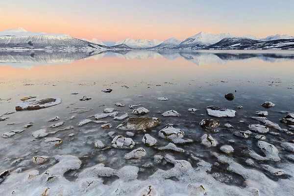 Cloudless sunrise with ice covering the stones on the shore of Balsfjorden. Markenes