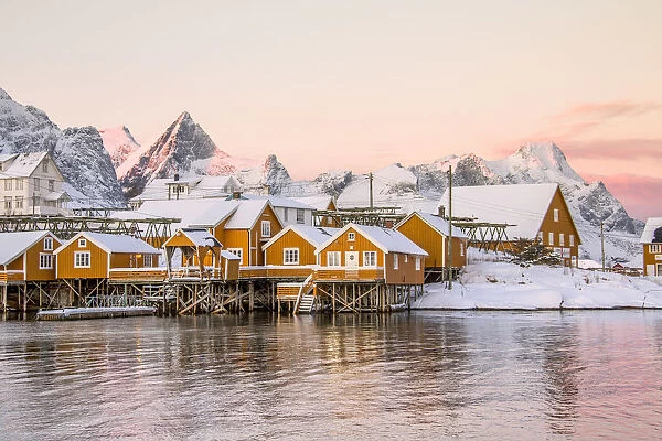 The colors of dawn frames the fishermen houses surrounded by snowy peaks Sakrisoy