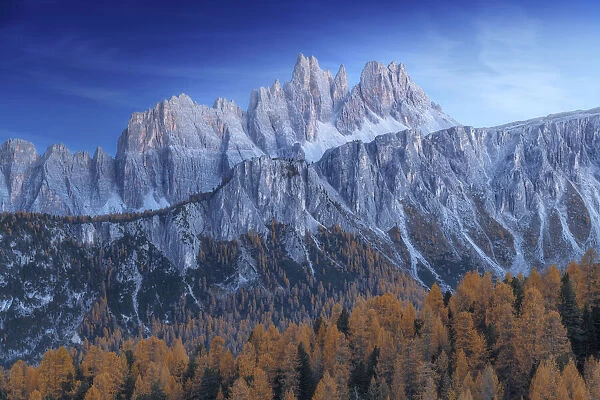 The Croda da Lago and Lastoi de Formin mountains at twilight, with the golden larches glowing in the darkness. Dolomites, Italy