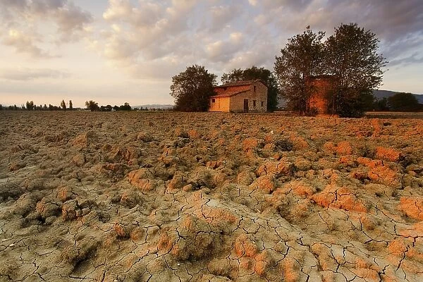Dry ground at sunset with a cottage in the background in the Umbrias countryside
