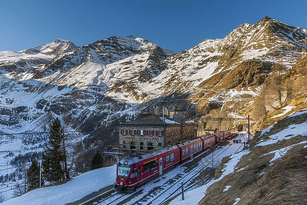 The famous Bernina Express red train at Alp Grum station in a scenic winter day