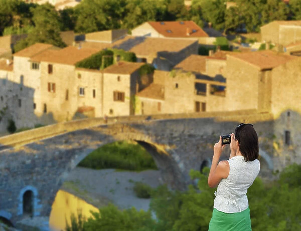 France, Languedoc, Lagrasse, woman photographing bridge (MR)