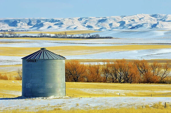 Grain bin and Big Muddy Badlands in background in winter south of Bengough, Saskatchewan, Canada