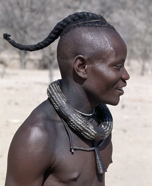 A Himba youth has his hair styled in a long plait, known as ondatu
