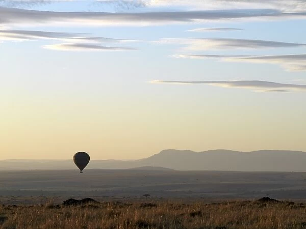 A hot air balloon floating over the Masai Mara Game Reserve at daybreak