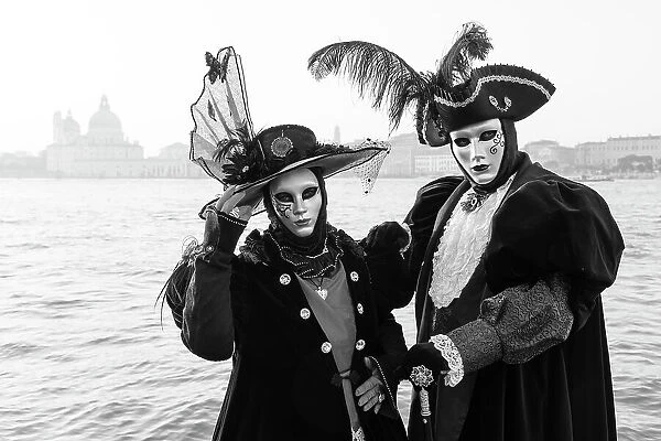 Italy, Veneto, Venice, a black and white version of a couple in costume in front of Salute during the Venice Carnival