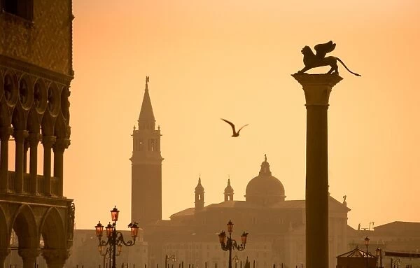 Italy, Veneto, Venice; The Palazzo dei Dogi, the bacino di San Marco with a sculpture of the lion of Venice and San Giorgio Maggiore in