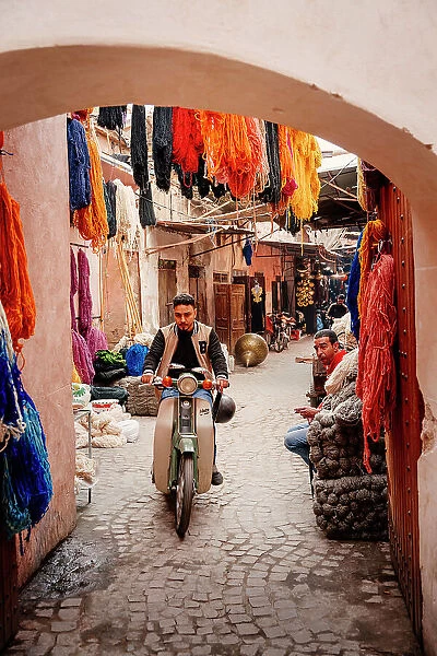 Man on a scooter through the colorful streets of the medina of Marrakech