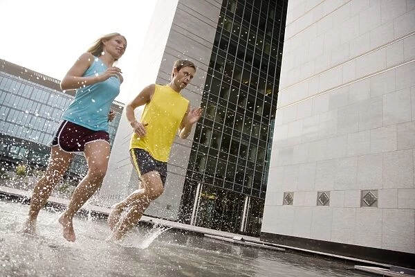 A man and woman running barefoot through water