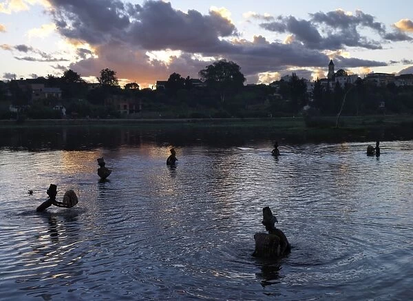 Men fish in Antsirabes lake at dusk using traditional