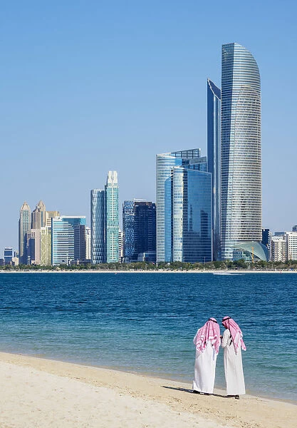 Two men wearing thawb on the beach and City Center Skyline, Abu Dhabi, United Arab
