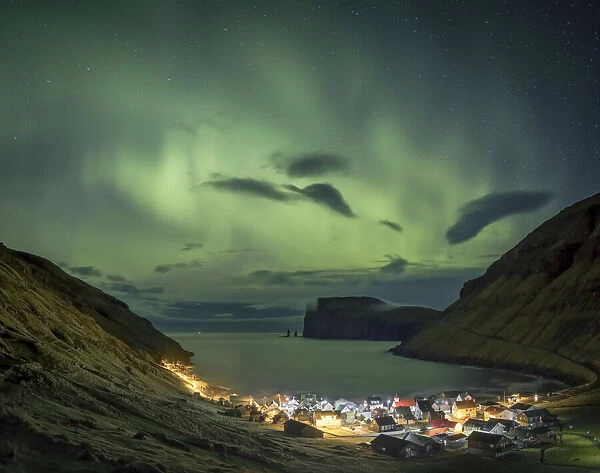 Northern lights above the village of TjornuvÔêÜÔëák. In the background Risin and Kellingin sea stacks. Streymoy island, Faroe Islands