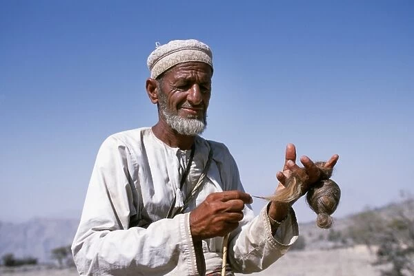 An old goatherd spins wool at his village on the rim