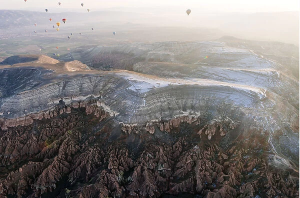 Overflight of Cappadocia with multicolored balloons at sunrise, snowy landscape. Turkey