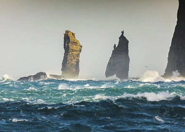Risin og Kellingin sea stacks hit by rough ocean. Eysturoy, Faroe Islands