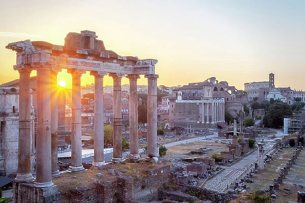 The Roman Forum at sunsrise, with Temple of Saturn in foreground and Colosseum in background, Rome, Lazio, Italy