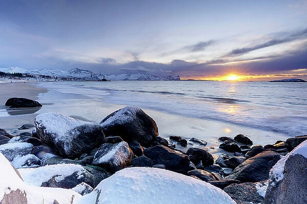 Romantic sky at sunset over the cold arctic sea washing the frozen Bovaer beach, Skaland, Senja, Troms county, Norway