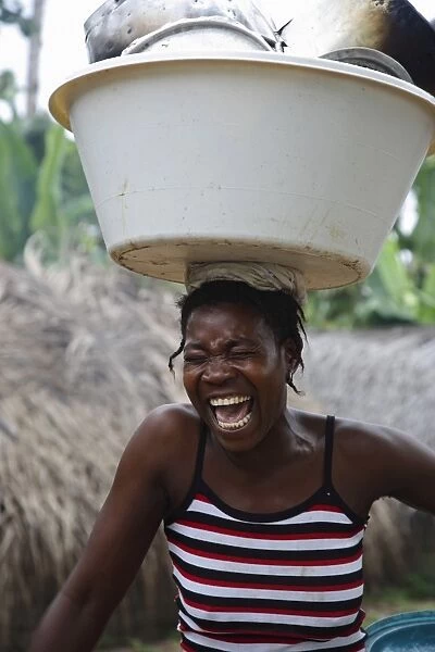 A Sao Tomense woman laughs while carrying her washing up on her head