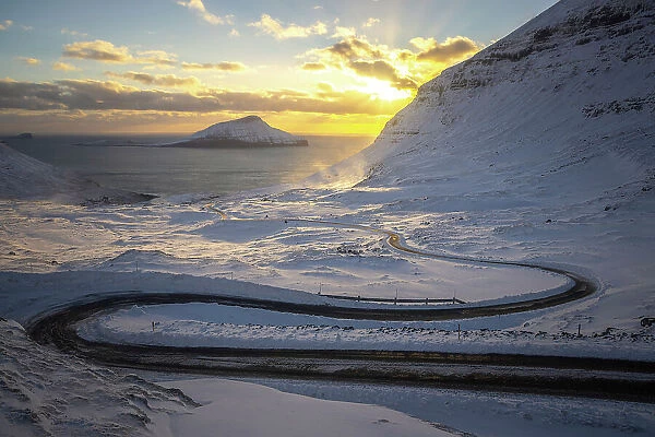 The scenic road in Norðradalur at sunset. Island of Streymoy. In the background the island of Koltur. Faroe Islands