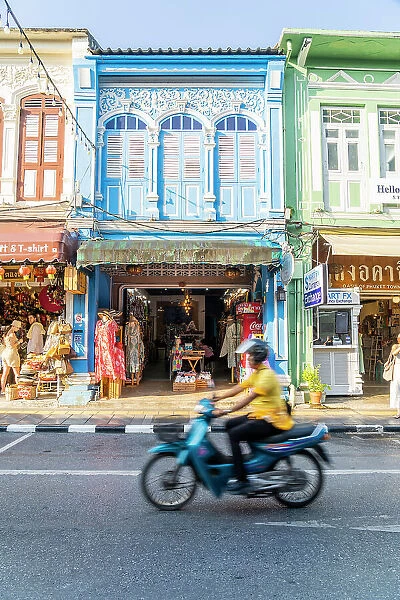 Scooter riding past beautiful buildings in the Old town, Phuket, Thailand