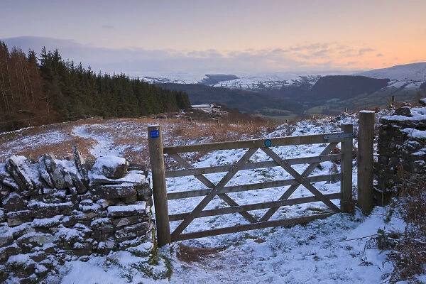 Snow covered gate and hilltop footpath on Allt yr Esgair with views to the Brecon Beacons mountains, Brecon Beacons National Park, Powys, Wales, UK. Winter (January) 2010