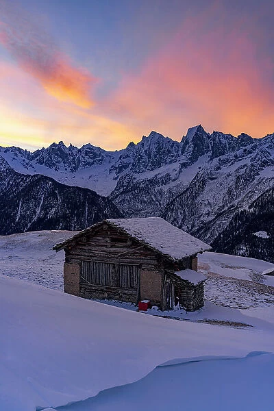 Sunrise over snowy mountains view from lone alpine chalet, Tombal, Soglio, Val Bregaglia, Graubunden, Switzerland