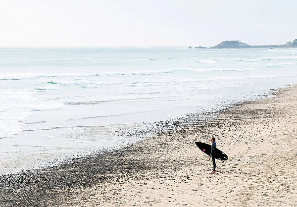 A surfer on the St Ouens Bay beach, Jersey, Channel Islands
